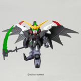 A small Gundam-style robot figure with black wings, a yellow and white head, green eyes, and a green blade, shown against a plain light gray background. A small 'SOTSU SUNRISE' copyright mark appears below the figure.