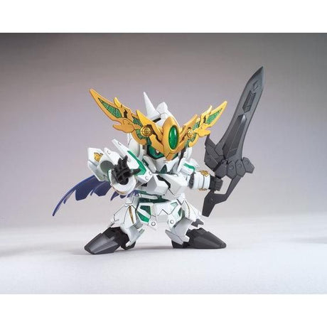 A small white mecha action figure holding a large dark gray sword, with gold wing-like armor details, green accents, and blue wing elements, photographed on a plain light gray studio background.