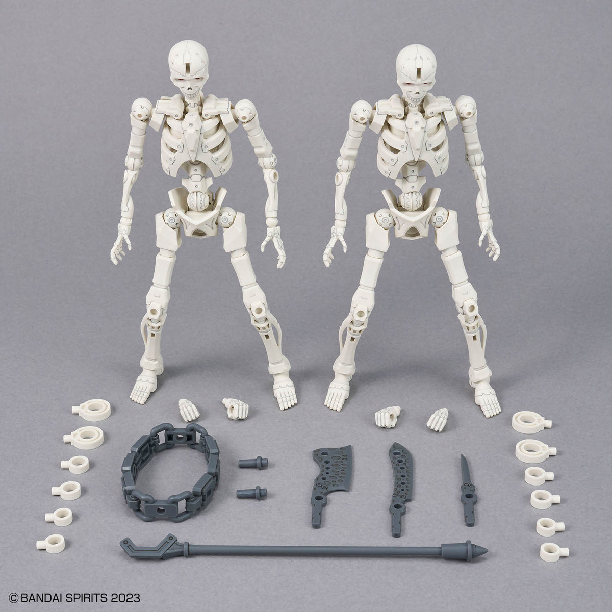 Two white action figure skeletons with attached parts on a gray background, featuring BANDAI SPIRITS branding.