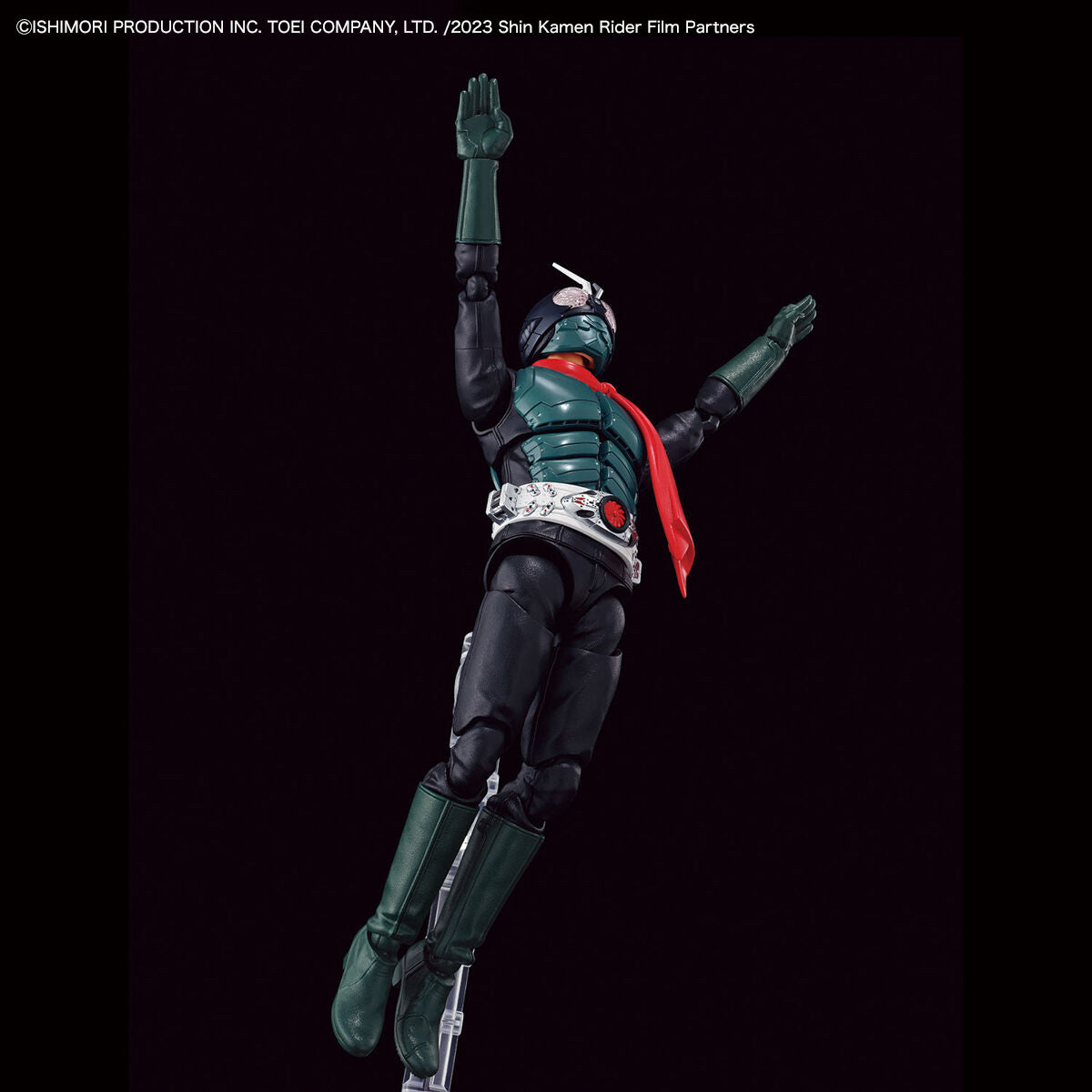 A collectible action figure of Kamen Rider in a dynamic jumping pose against a solid black background. The figure features a dark green and black bodysuit with a bright red cape and silver belt details.