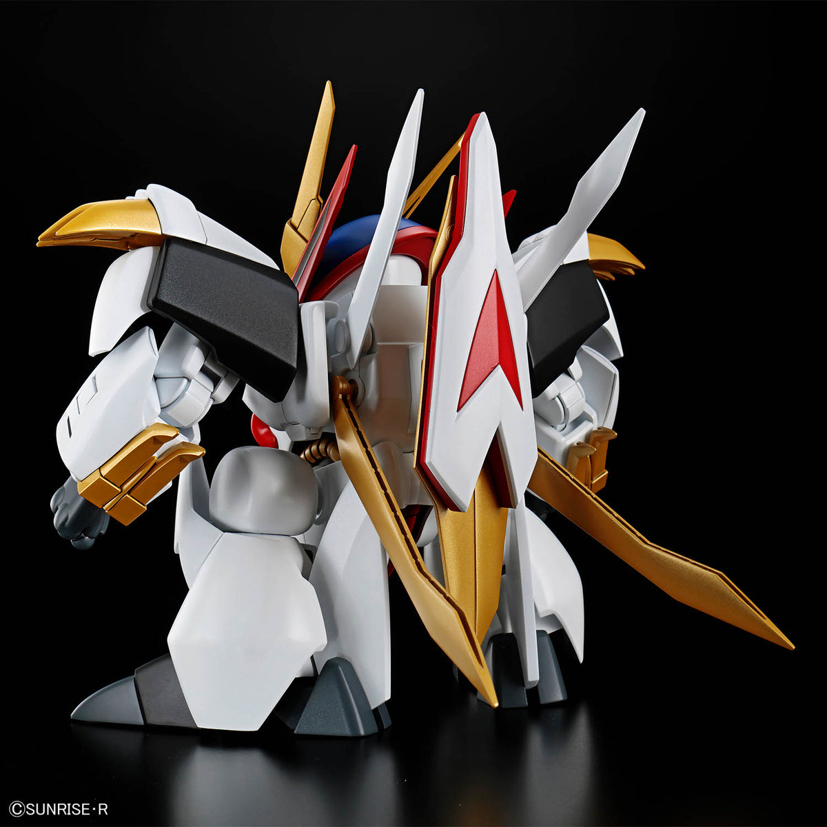 Model kit of a robot with gold, white, and red details on a black background