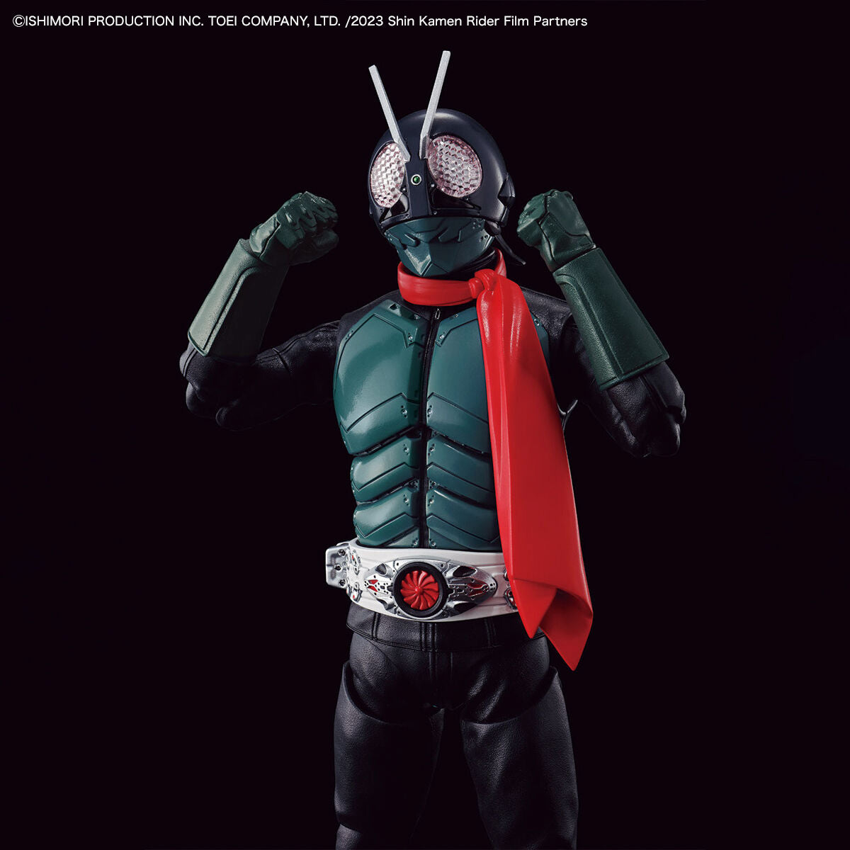 Kamen Rider Shin Kamen Rider action figure posed with arms raised, wearing a dark green and black bodysuit with a bright red cape and silver belt, set against a solid black background.