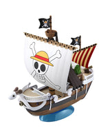 A small wooden toy pirate ship displayed on a blue stand against a plain white background. The ship has a large white sail printed with a skull-and-crossbones wearing a yellow straw hat, plus black pirate flags and striped sails.
