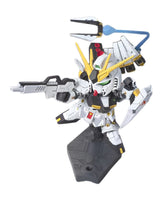 A small white, yellow, black, and gray mecha figurine posed on a black display base, holding a rifle and a blue trident-like accessory, against a plain white background.
