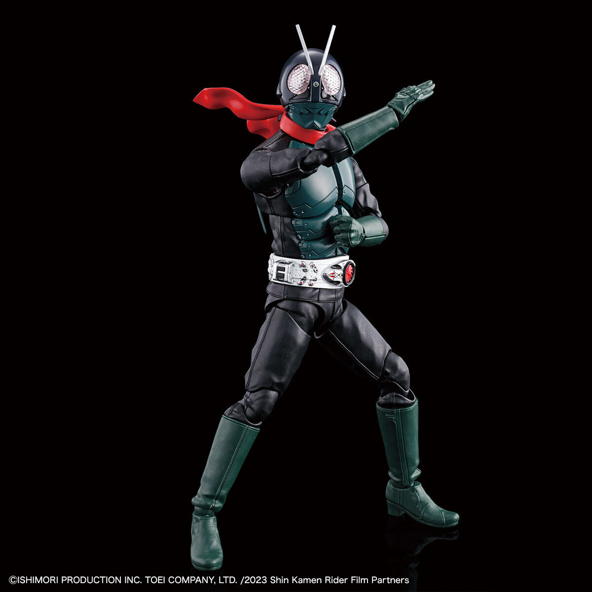 Shin Kamen Rider action figure posed in a dynamic fighting stance against a solid black background. The figure features a black and dark green bodysuit, a silver helmet with two antennae, a bright red cape, and a silver belt with a red Geki-Geki token.